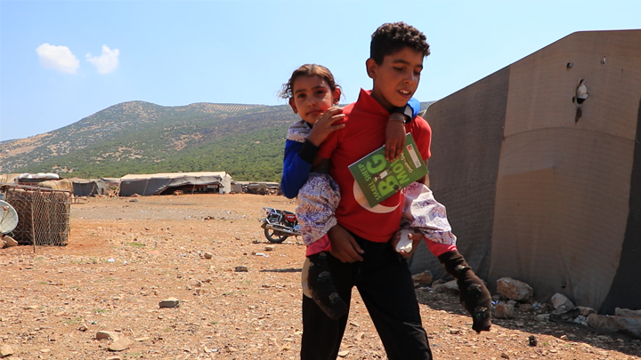 منال طفلة مهجرة في عفرين.. لم يمنعها المرض من الذهاب إلى المدرسة ولو على ظهر شقيقها