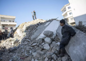 طفل سوري يجلس فوق ركام المنازل المدمرة في سوريا