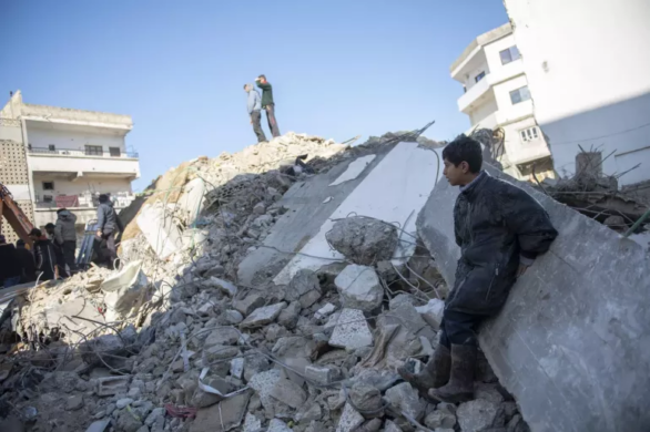 طفل سوري يجلس فوق ركام المنازل المدمرة في سوريا