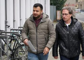 ينس واليش (يمين) يرافق أحمد أحمد (يسار) إلى الموعد في مكتب الهجرة.